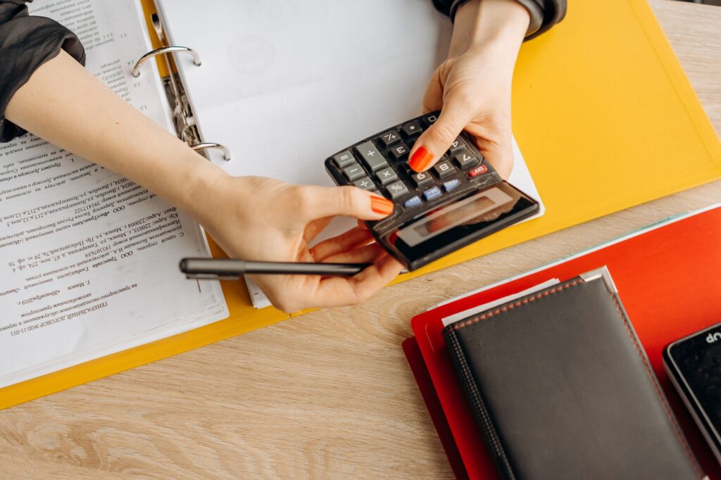 restaurant bookkeeping — hands using a calculator at a desk with documents and folders, ideal for finance or accounting theme