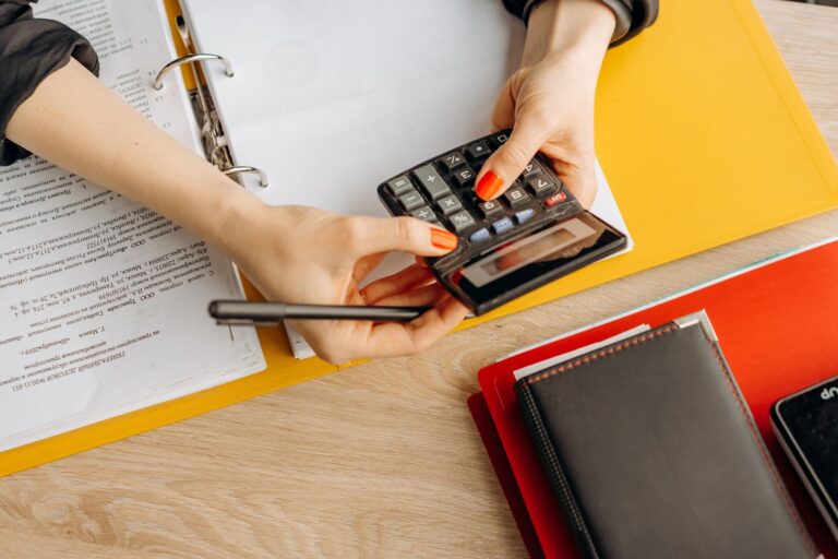 restaurant bookkeeping — hands using a calculator at a desk with documents and folders, ideal for finance or accounting theme