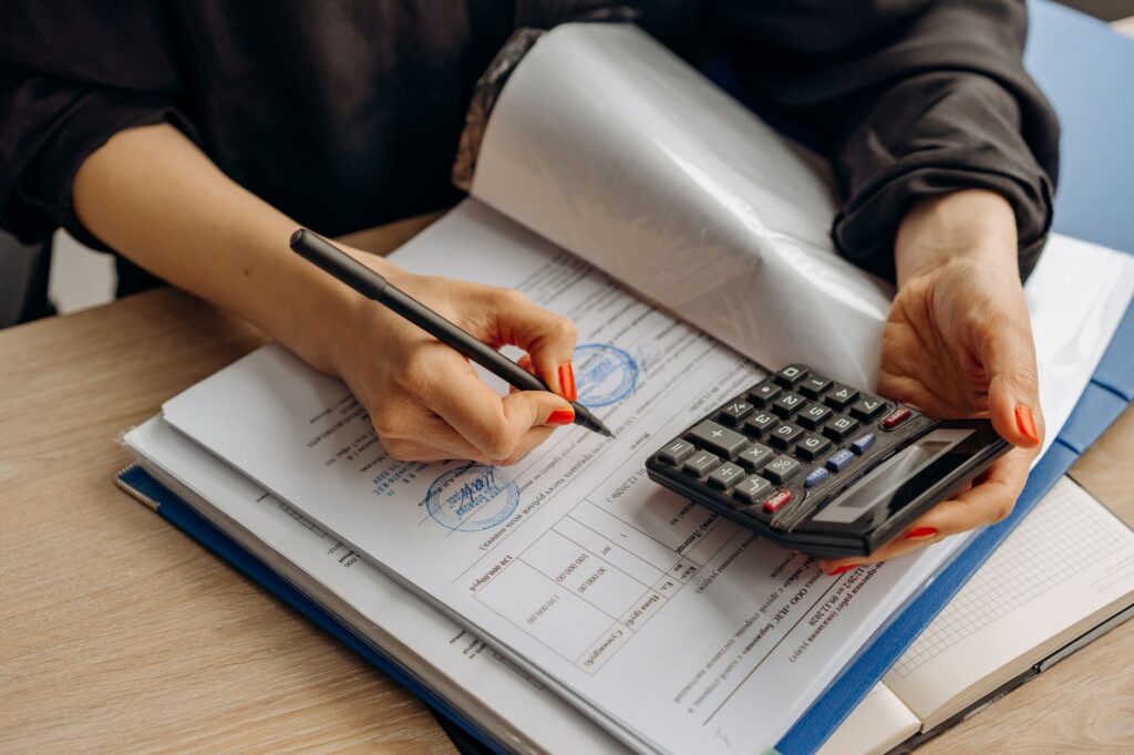 trucking bookkeeping software — an accountant using a calculator and signing paperwork, showcasing financial analysis.