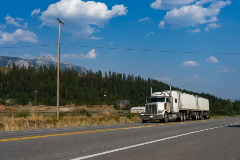 trucking company factoring service — a white semi-truck traveling on a scenic road in jaffray, bc, with mountains in the back